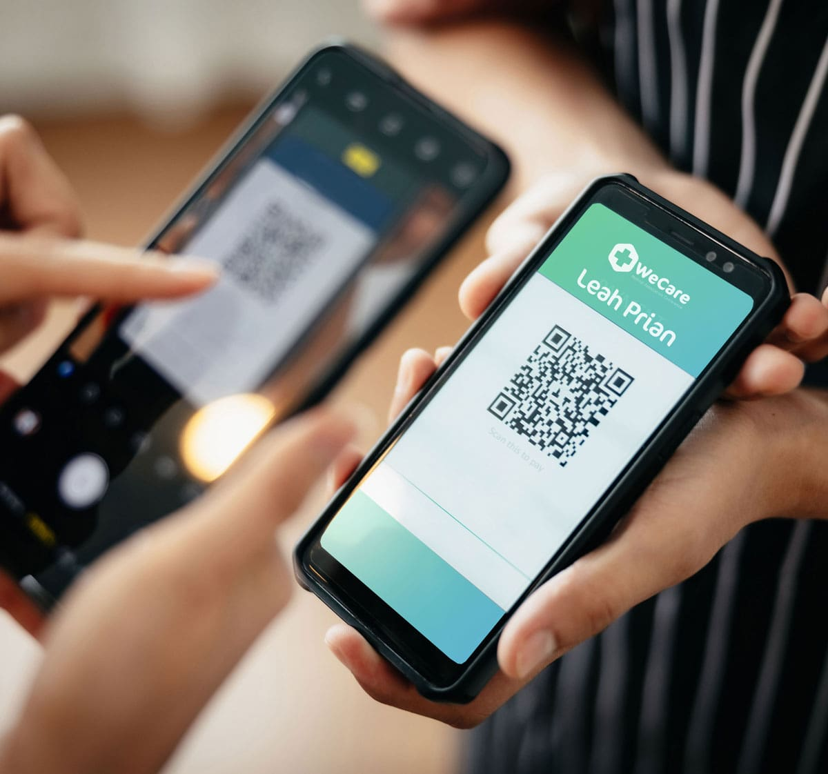 A QR code displayed on one phone screen being read by the camera of a second phone held alongside it